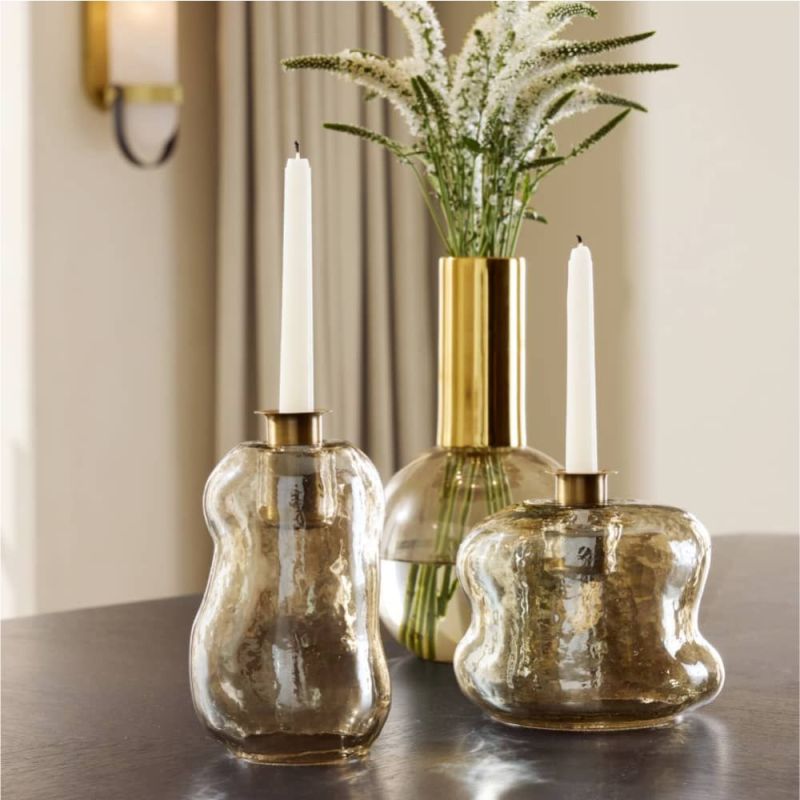 Free-form glass candleholders with a smoky luster finish and antique brass tops, shimmering in the light.