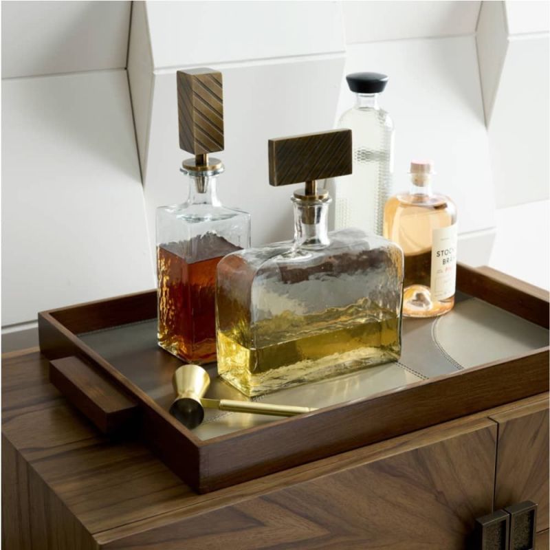 Hammered glass decanters with embossed brass and nickel stoppers inspired by classic tie patterns.