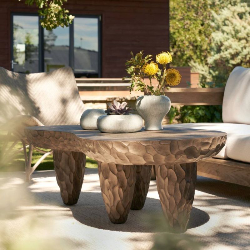 Kidney-shaped outdoor coffee table with smooth top and carved underside