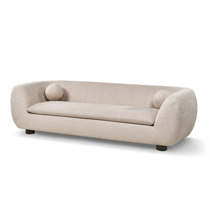 A stylish sofa with a curved design, ball scatter cushions and beige upholstery