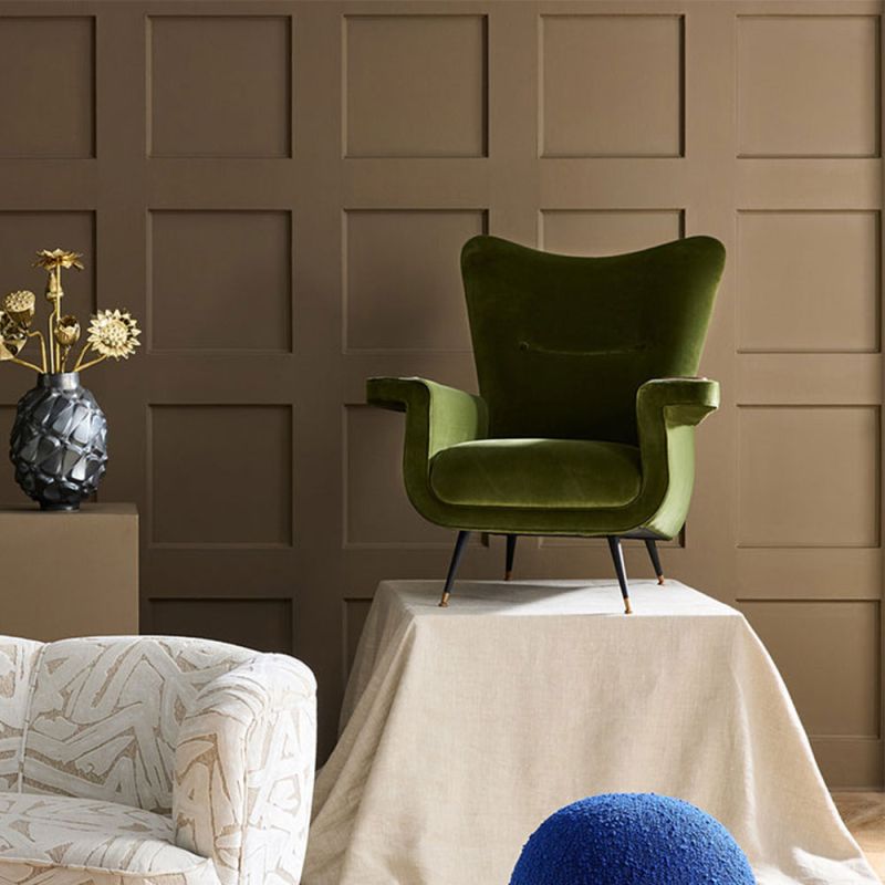 The Pierre Lounge Chair features a swooping silhouette, emerald velvet upholstery, and a built-in wood coaster, making it a glamorous addition to any space.