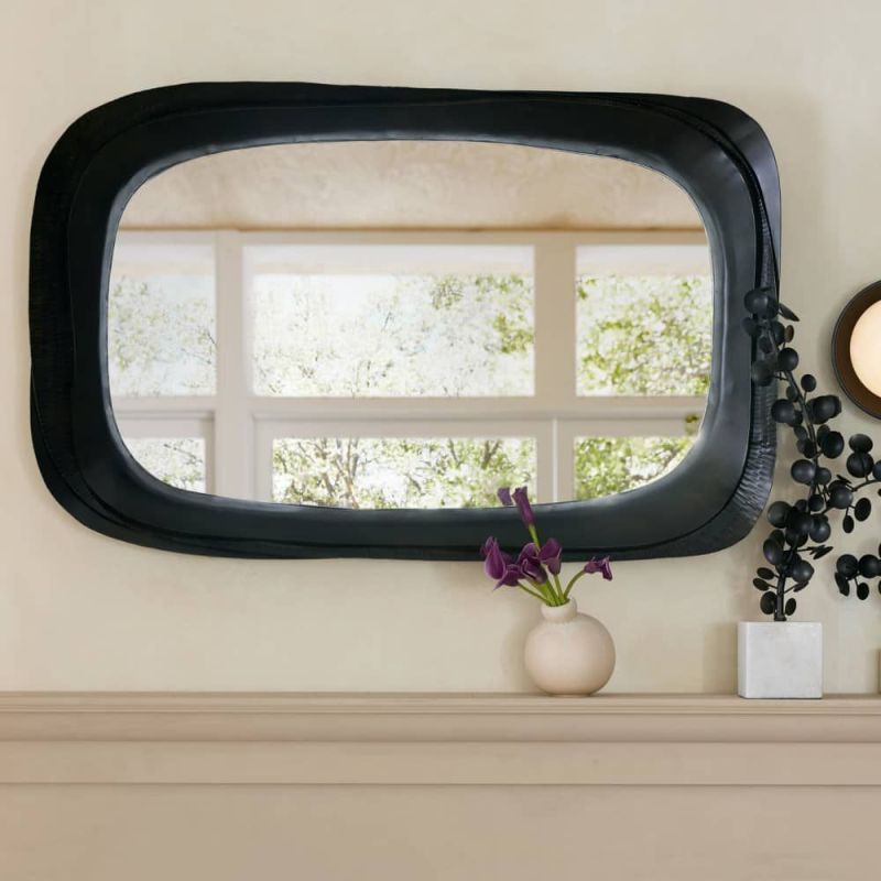 The Fitzhugh Mirror features a forged iron frame with petal-like curves, a bronze finish, and versatile vertical or horizontal display.