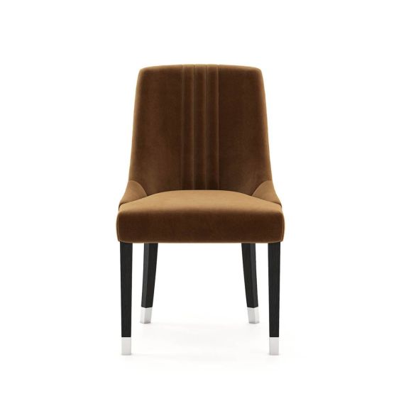 A timelessly elegant dining chair upholstered in velvet with black legs and golden caps. Pictured in Vienna Teja.