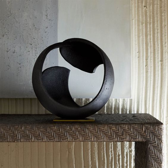 Round black stone sculpture on brass base