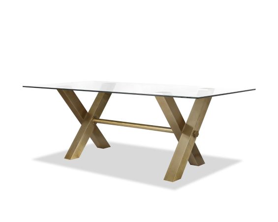 Artisan-crafted dining table with brass legs topped with an expanse of toughened clear glass