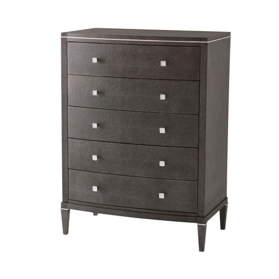 A tall chest of drawers with a luxury design featuring embossed leather, tapered legs and polished nickel adornments