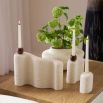 Set of three sculptural candleholders in cream with naturally textured surfaces and wooden accents.