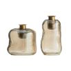 Free-form glass candleholders with a smoky luster finish and antique brass tops, shimmering in the light.