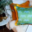 A gorgeous green cushion with a blue pattern and an elegant mustard fringe