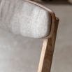 Contemporary wooden dining chair with gently curved back rails upholstered in lovely neutral fabric