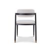 Boucle upholstered dining chair with slanted black legs and brass caps on the feet