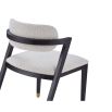 Boucle upholstered dining chair with slanted black legs and brass caps on the feet