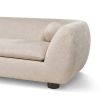 A stylish sofa with a curved design, ball scatter cushions and beige upholstery