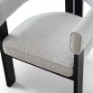 Grey linen armchair with rounded back and three black legs 