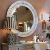 Circular wall mirror in white washed wood with intricate carvings