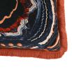 Black cushion with brown and blue swirl pattern and orange fringe