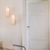 Contemporary solid brass wall lamp in a polished nickel finish with a long translucent glass lampshade