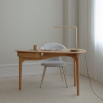 Wooden desk in a rounded triangle silhouette, complete with three legs and a drawer