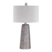 This lamp has a textured rustic bronze base with a grey wash, nickel accents, and a beige linen shade for a refined look.