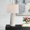 This tapered ceramic lamp has a distressed off-white finish, brushed nickel accents, and a white linen shade, adding timeless elegance to any space.