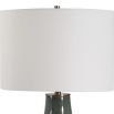 This ceramic table lamp features a bluish-green finish with rust undertones, brushed brass accents, and a white linen shade, adding sophisticated charm to any space.