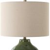 This elegant ceramic lamp has a moss green glaze, brass accents, and a beige linen shade.