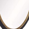 Black oval wooden mirror with brass detailing on inner circle