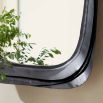 The Fitzhugh Mirror features a forged iron frame with petal-like curves, a bronze finish, and versatile vertical or horizontal display.