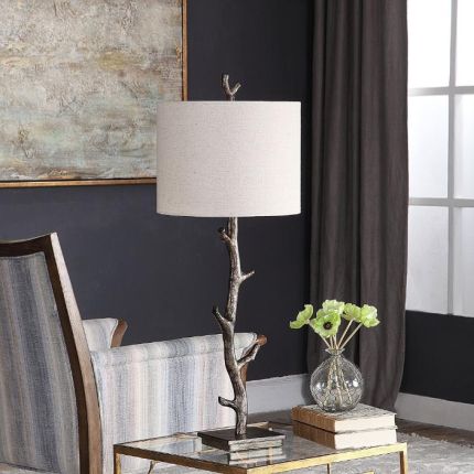 This rustic table lamp features a deep bronze finish with silver undertones and an off-white linen shade